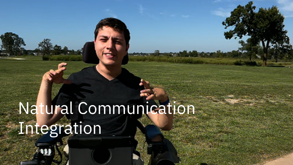 Man outside in his wheelchair with his AAC system in front of him. The text "Natural Communication Integration" is overlayed.